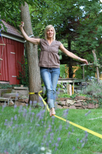 Frau auf Slackline im Garten