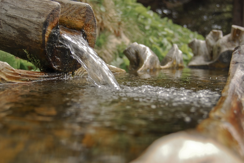 Fließendes Wasser aus einem Holzbrunnen - Nahaufname 