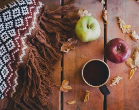 Wolldecke, Äpfel und Becher auf Holztisch